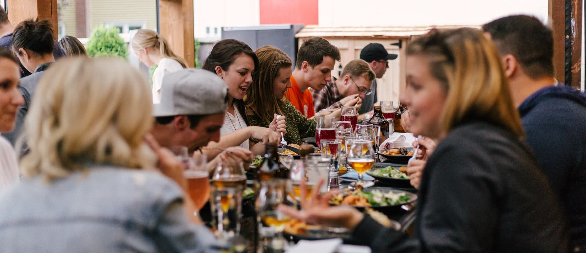 Guests talking and eating together along a long shared table