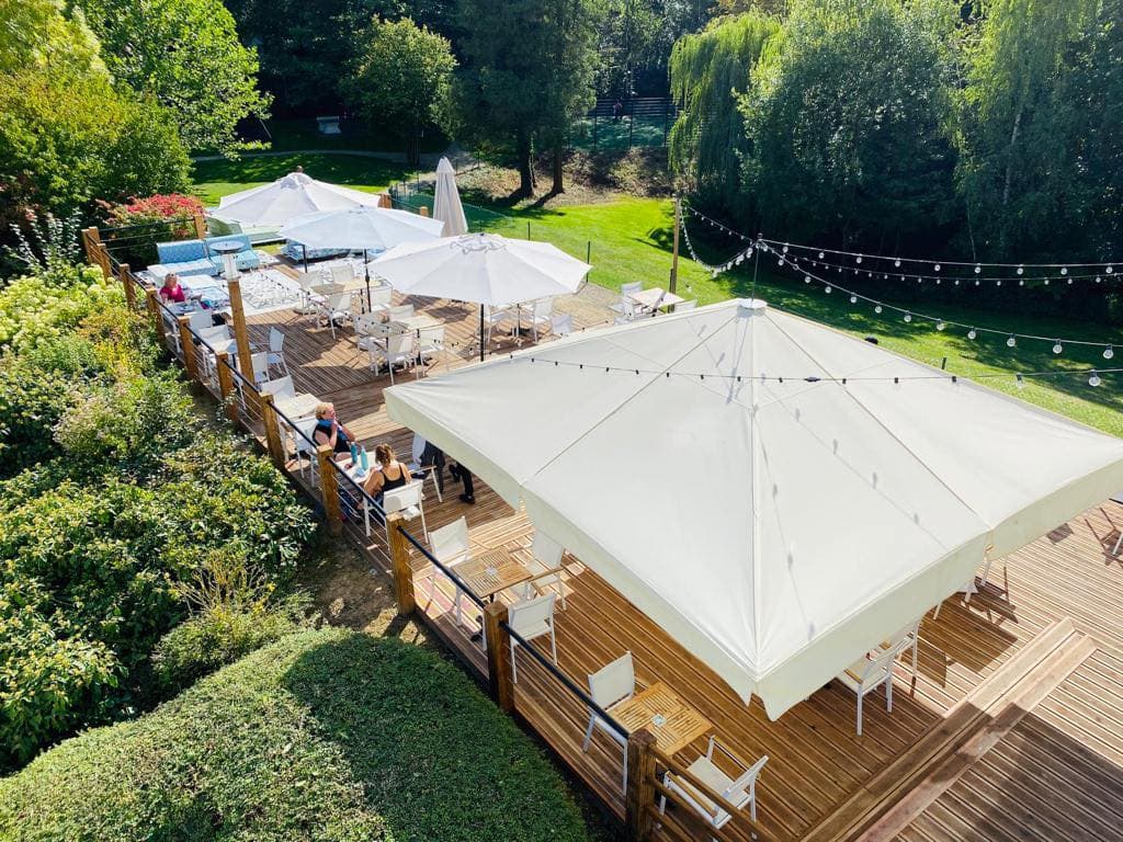 Garden terrace with parasols and festoon lighting above wooden decking